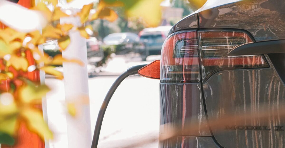 Close-up of an electric car connected to a charging station outdoors in sunlight