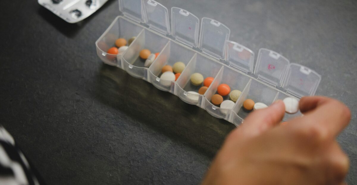person about to pick medicine from medicine organizer