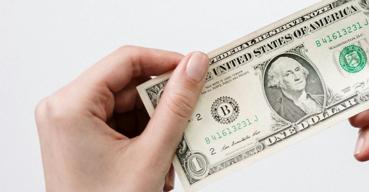 Hands holding a one dollar bill depicting currency and finance closely