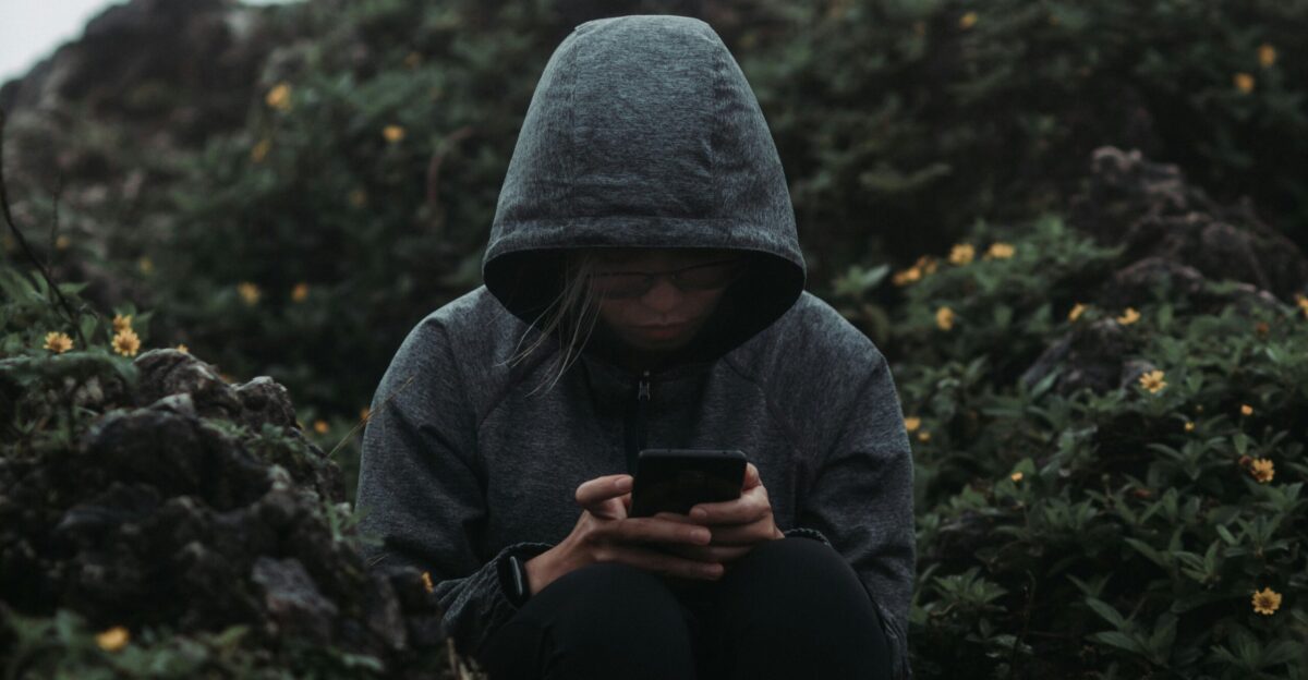 a person sitting on a rock looking at a cell phone