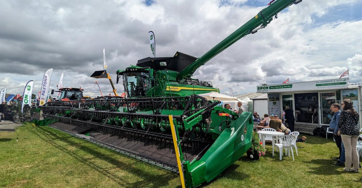 Green combine harvester displayed at an outdoor agricultural show in Harrogate showcasing farming technology