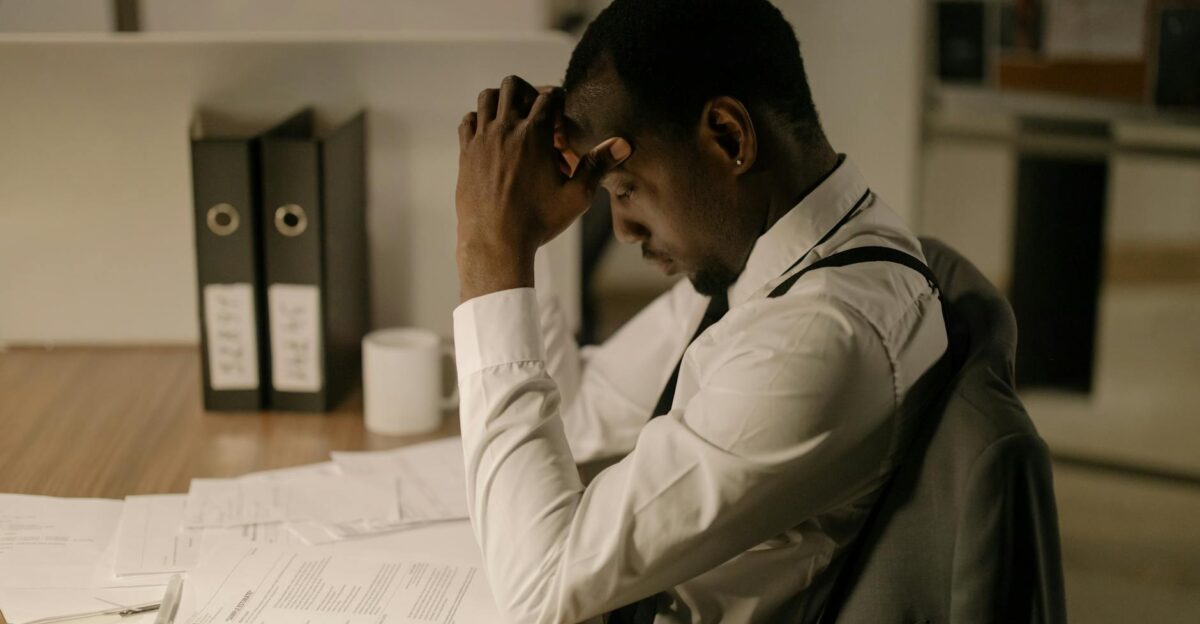 An adult man in an office is concentrating on documents reflecting stress and focus in a work environment