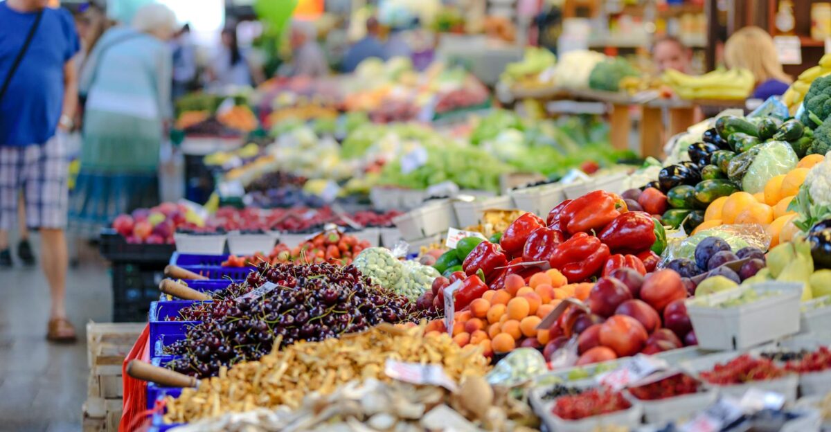 Colorful assortment of fresh fruits and vegetables in a bustling outdoor market scene