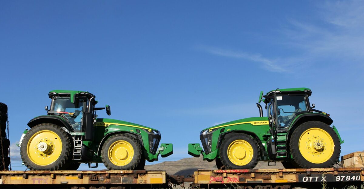 a couple of green tractors sitting on top of a train