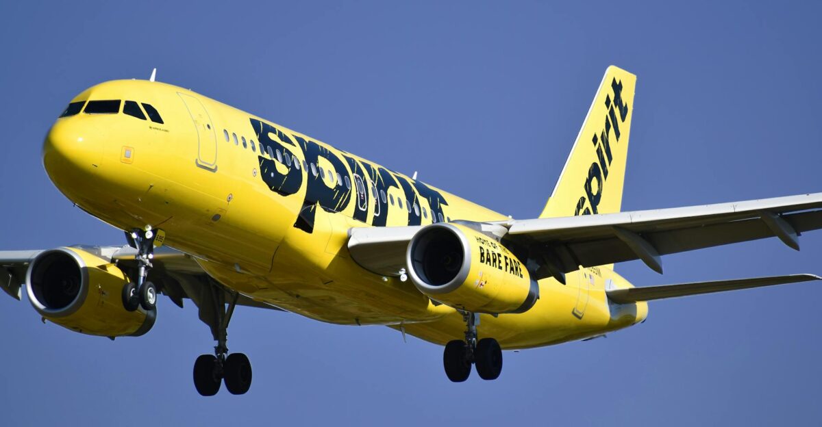Yellow Spirit Airlines aircraft captured mid-air against a clear blue sky