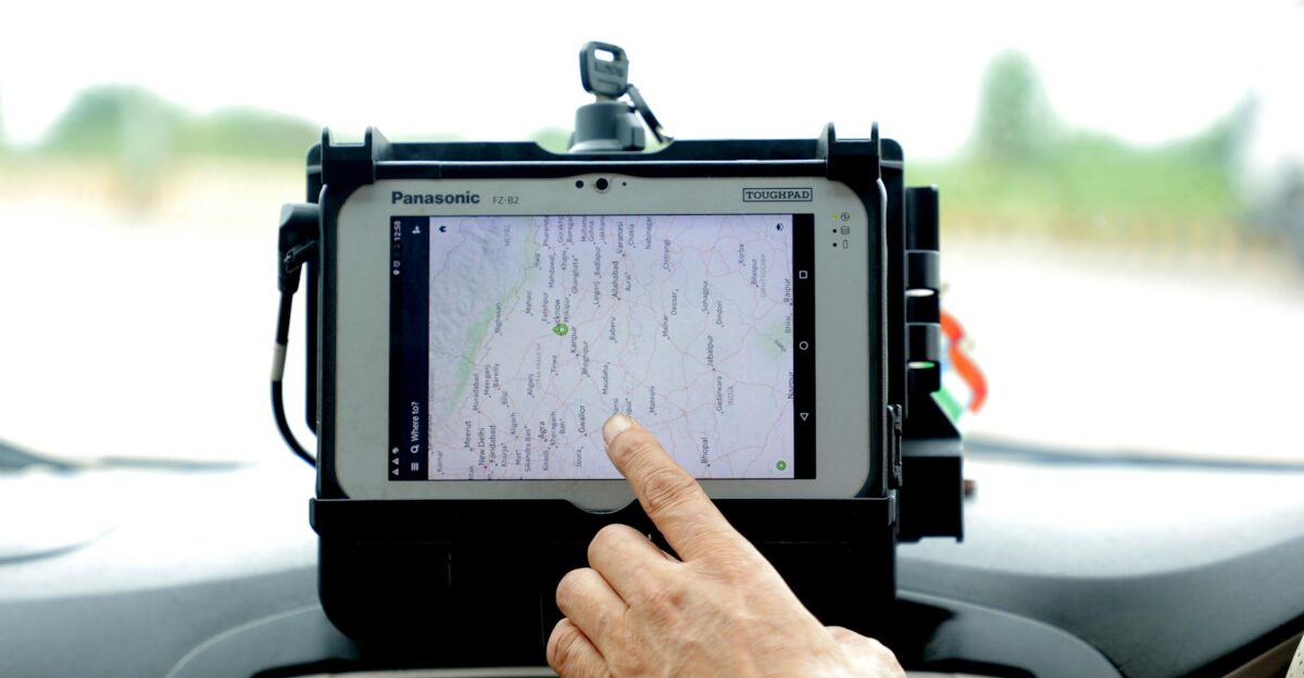 Close-up of hand interacting with GPS navigation on a car-mounted tablet screen showcasing modern technology