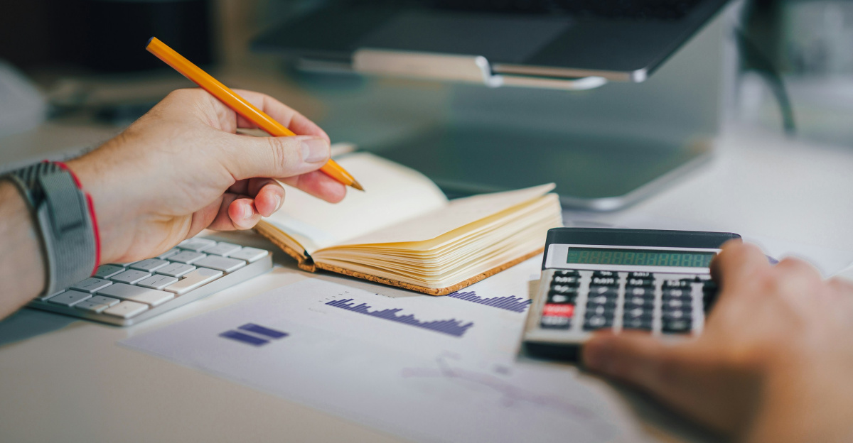 a person sitting at a desk with a calculator and a notebook